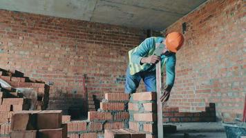 ein baumeister auf einer baustelle legt ziegel in das haus. Baumeister Mauerwerk Lüftungskanal. video