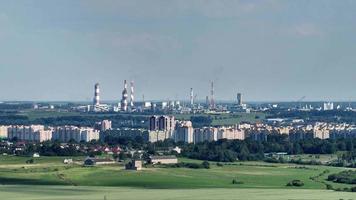 ariel panoramisch uitzicht over stad en wolkenkrabbers met een enorme fabriek met rokende schoorstenen op de achtergrond video