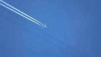 Jet airliner flying high in the sky leaving contrails in the clear blue sky. video