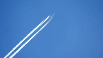 avião a jato voando alto no céu deixando rastros no céu azul claro. video