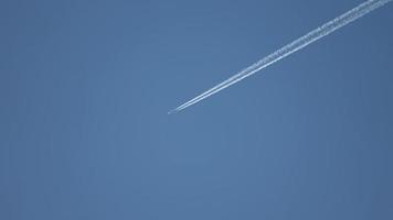 Jet airliner flying high in the sky leaves contrails in the clear blue sky. video