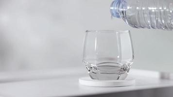 Wasser in Glas auf Holztisch gießen. video