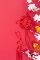 Design concept of Chinese lunar new year - Beautiful Chinese knot with plum blossom isolated on red background, flat lay, top view, overhead layout. photo