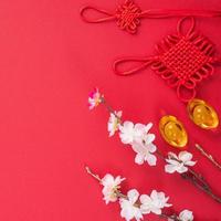 Design concept of Chinese lunar new year - Beautiful Chinese knot with plum blossom isolated on red background, flat lay, top view, overhead layout. photo