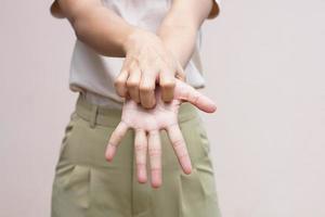 Woman scratching arm from itching on light gray background. Cause of itchy skin include insect bites Concept of health care skin. photo