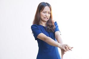 Woman scratching arm from itching on light gray background. Cause of itchy skin include insect bites Concept of health care skin. photo