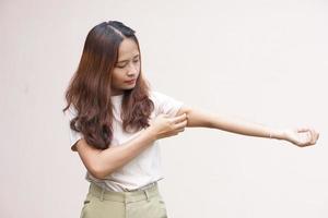 Woman scratching arm from itching on light gray background. Cause of itchy skin include insect bitesConcept of health care skin photo