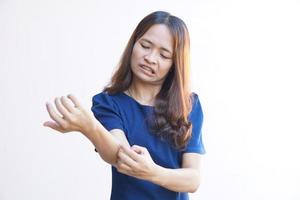 Woman scratching arm from itching on light gray background. Cause of itchy skin include insect bites Concept of health care skin. photo