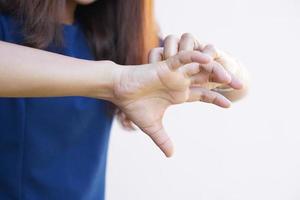 Woman scratching arm from itching on light gray background. Cause of itchy skin include insect bites Concept of health care skin. photo