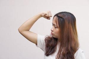 las mujeres asiáticas flexionan sus músculos y muestran su fuerza. foto