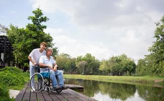 Asian careful caregiver or nurse hold the patient hand and encourage the patient in a wheelchair. Concept of happy retirement with care from a caregiver and Savings and senior health insurance. photo