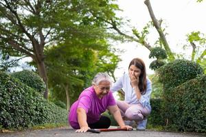 Asian senior woman fell down on lying floor because faint and limb weakness and Crying in pain form accident and her daughter came to help support. Concept of old elderly insurance and health care photo
