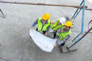 Top view of Asian engineer or Young Female Architect put on a helmet for safety and talk with a contractor on a construction building factory project, Concept of Teamwork, Leadership concept. photo