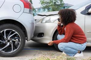 Asian women driver check for damage after a car accident before taking pictures and sending insurance. Online car accident insurance claim after submitting photos and evidence to an insurance company.