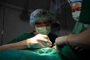 Asian Professional surgeons team performing surgery in the operating room, surgeon, Assistants, and Nurses Performing Surgery on a Patient, health care cancer and disease treatment concept photo