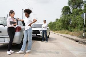 Women drivers Talk to Insurance Agent for examining damaged car and customer checks on the report claim form after an accident. Concept of insurance, advice auto repair shop and car traffic accidents. photo