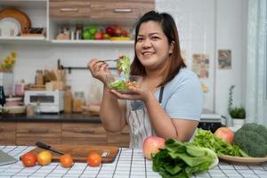 las embarazadas asiáticas aprenden a cocinar comidas saludables de Internet en la cocina, las mujeres gordas preparan una ensalada de verduras para la dieta y pierden peso. concepto de alimentación saludable