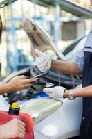 Asian women get contact numbers from auto mechanics after fixing the car engine problem and QR code scan to pay for gas after running out of fuel on the road. Car repair and maintenance concept. photo