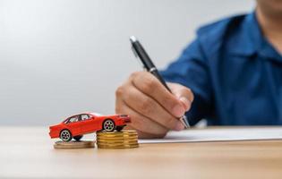 Unhappy Asian man holding a banknote and Making an account of income and expenses to pay the home loan and car loan, Concept loan payment and home insurance, economic problems, and inflation photo