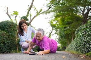 Asian senior woman fell down on lying floor because faint and limb weakness and Crying in pain form accident and her daughter came to help support. Concept of old elderly insurance and health care photo