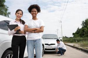 Women drivers Talk to Insurance Agent for examining damaged car and customer checks on the report claim form after an accident. Concept of insurance, advice auto repair shop and car traffic accidents. photo