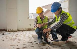 Engineer teaching worker for use electric jackhammer for perforator equipment making holes the floor to be strong at construction site, Concept of worker and residential building photo
