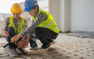 Engineer teaching worker for use electric jackhammer for perforator equipment making holes the floor to be strong at construction site, Concept of worker and residential building photo