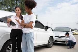 Women drivers Talk to Insurance Agent for examining damaged car and customer checks on the report claim form after an accident. Concept of insurance, advice auto repair shop and car traffic accidents. photo