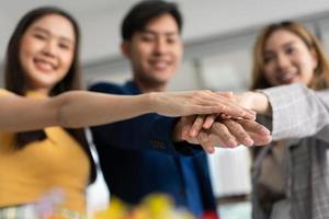 Business team join hand after Successful of new business startup, people working together in creative office, happy euphoric proud Asian male and female professional winner feel overjoyed photo