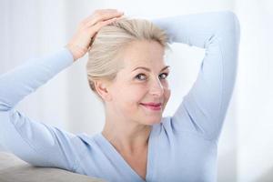 Active beautiful middle-aged woman smiling friendly and looking in camera. Woman's face closeup. Realistic images without retouching with their own imperfections. Selective focus. photo