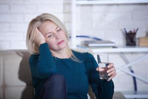 mujer bebiendo concepto alcohólico de problemas sociales sentado en casa en un estado deprimido. mujer de mediana edad sosteniendo un vaso pidiendo ayuda. foto