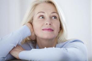 Active beautiful middle-aged woman smiling friendly and looking in camera. Woman's face closeup. Realistic images without retouching with their own imperfections. Selective focus. photo