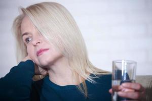 mujer bebiendo concepto alcohólico de problemas sociales sentado en casa en un estado deprimido. mujer de mediana edad sosteniendo un vaso pidiendo ayuda. foto
