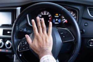 hombre tocando la bocina mientras conduce sentado en un coche de prensa del volante, tocando la bocina para advertir a otras personas foto