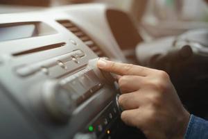 cierre la mano abierta escuchando la radio del coche. Conductor de camión cambiando las estaciones de radio de botón de giro en el sistema multimedia de su vehículo. moderno sistema de audio estéreo con pantalla táctil. concepto de transporte y vehículo foto