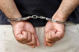 Prisoner male criminal standing in handcuffs with hands behind back. photo