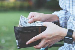 Man standing holding black wallet full of money photo