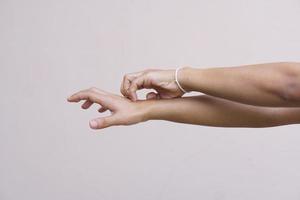 mujer rascándose el brazo por picazón en un fondo gris claro. la causa de la picazón en la piel incluye el concepto de picaduras de insectos de la piel para el cuidado de la salud. foto