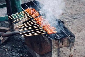 Photo of a satay being grilled on a grill in a market area in Bali.