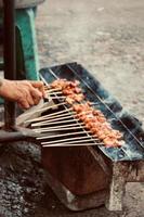 Photo of a satay being grilled on a grill in a market area in Bali.