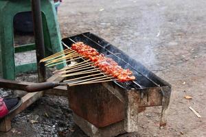 Photo of a satay being grilled on a grill in a market area in Bali.