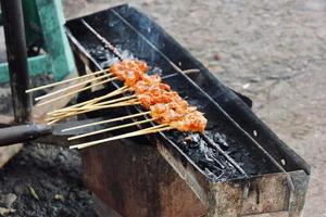 Photo of a satay being grilled on a grill in a market area in Bali.