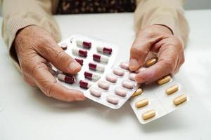 Asian elderly woman holding pill drug in hand, strong healthy medical concept. photo