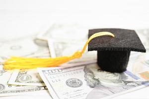 sombrero de la brecha de graduación en el dinero de los billetes en dólares estadounidenses, concepto de enseñanza de aprendizaje de la tarifa de estudio de educación. foto