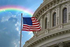 Washington DC Capitol with waving flag on rainbow sky background photo