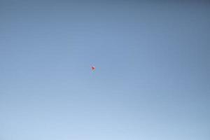 Red ball in blue sky. Balloon flies in air. photo