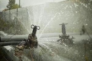 Pipeline accident. Burst pipe. Water pours outside. Pressure loss in water supply. photo