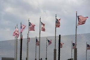 Waving usa flags behind fence grid photo