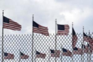 Waving usa flags behind fence grid photo