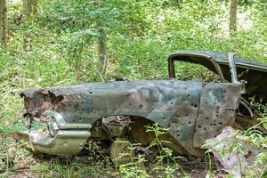 viejo coche oxidado abandonado en el bosque con agujeros de bala foto